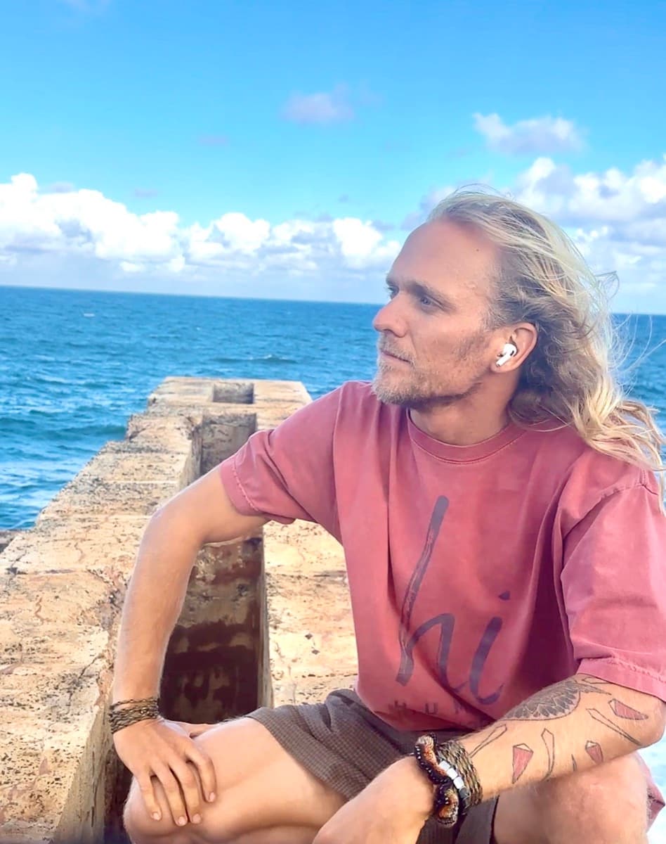 Alex wearing the HI Classic Tee and HI Cap at an ocean overlook, Kauai, HI